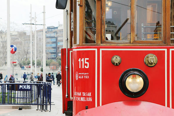 Picture of a red tram with city squre in the background.